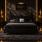 A black upholstered bed with a Batman-themed headboard, styled with dark gray and black bedding and decorative pillows in a minimalist gray bedroom.