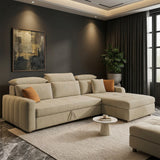 A modern beige sectional sofa with a chaise lounge in a bright, contemporary living room. The sofa features tufted cushions, a low back, and is styled with a single orange accent pillow.